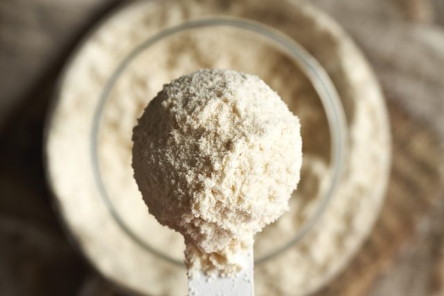 Whey,Protein,Powder,In,A,Scoop,Above,A,Jar,,Top